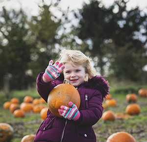 A young girl with her pumpkin waves at the camera at the National Forest Adventure Farm, Staffordshire